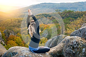 Sporty fit woman is practicing yoga on the top of the mountain