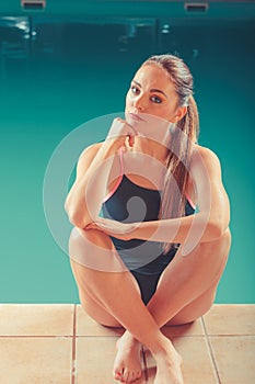 Sporty fit woman at swimming pool edge poolside.