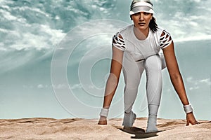 Sporty and fit young woman athlete on startline before running at the desert. Cloudy day on coast. The concept of a