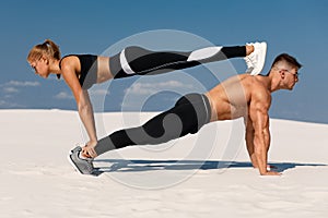 Sporty fitness couple doing planking exercise outdoors. Beautiful athletic man and woman workout photo