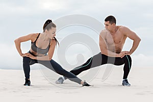 Sporty fitness couple doing stretching exercises outdoors. Beautiful athletic man and woman