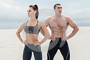 Sporty fitness couple showing muscle outdoors. Beautiful athletic man and woman, muscular torso abs photo