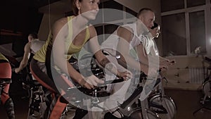 Sporty fitness group of three training on stationary bikes doing exercise synchronously