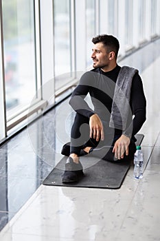 Sporty fitness man resting, having break drinking water after doing exercise