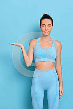 Sporty fitness woman standing and holding invisible item with blank space for advertise text. Good shape slim and