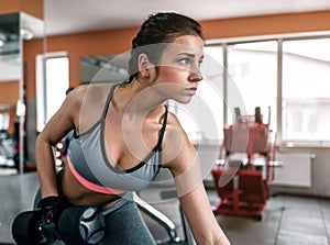 Sporty girl doing exercises with dumbbell in the gym