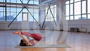 sporty girl doing Pilates exercises in a studio with large windows