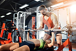 Sporty girl doing weight exercises with assistance of her personal trainer at gym.