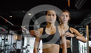 Sporty girl doing weight exercises with the help of her personal trainer at the gym