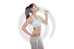 Sporty girl drinking water from a bottle after a workout, fitness training, isolated on white background