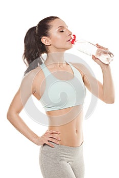 Sporty girl drinking water from a bottle after a workout
