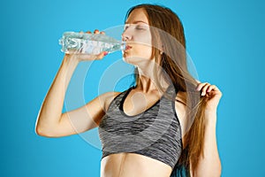 Sporty girl drinking water from clear plastic bottles