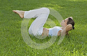 Sporty girl exercising on meadow against the sky