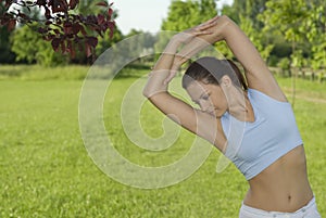 Sporty girl exercising on meadow against the sky