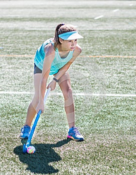 Sporty girl holding hockey stick standing ready to hit hockey ball