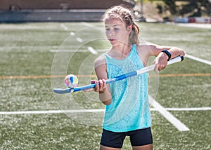 Sporty girl hopping a hockey ball on her hockey stick.