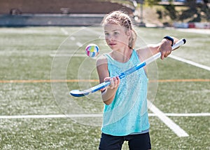 Sporty girl hopping a hockey ball on her hockey stick.