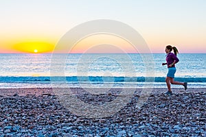 Sporty Girl jogging on Beach along Sea Surf at Sunrise