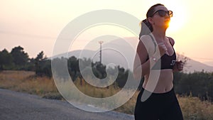 Sporty girl jogging in country road at sunset. Young woman running outdoors. Healthy active lifestyle. Slow motion Close