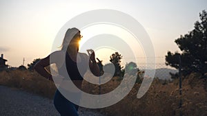 Sporty girl jogging in country road at sunset. Young woman running outdoors. Healthy active lifestyle. Slow motion Close