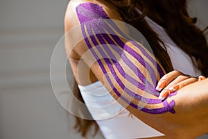 Sporty girl with kinesio tape on her arm. Fixation of the muscles of the biceps with a plaster for kinesitherapy
