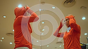 Sporty girl looks in mirror and try outfits in modern shopping centre department store.Happy shopper girl posing in