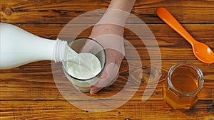 Sporty girl pours almond milk into a glass in the kitchen, slow motion