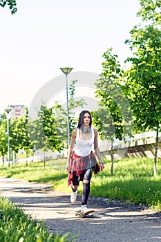 Sporty girl riding skateboards on street. Outdoors, urban lifestyle