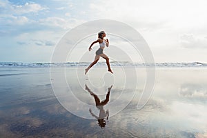 Sporty girl running by beach along sea surf