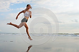 Sporty girl running by beach along sea surf