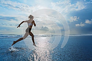 Sporty girl running by beach along sea surf