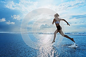 Sporty girl running by beach along sea surf