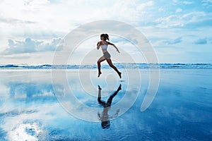 Sporty girl running by beach along sea surf