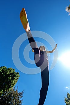 Sporty girl running in the sun and jumping over camera, view from below, copy space