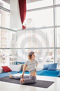 Sporty girl sitting in Half lord of the fishes, Ardha Matsyendrasana pose.