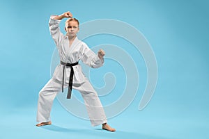 Sporty girl standing in stance and training karate in studio