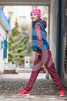 Sporty girl stretching outdoor on city street.