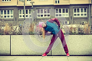 Sporty girl stretching outdoor on city street.