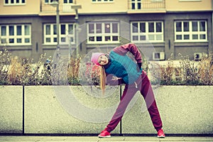 Sporty girl stretching outdoor on city street.