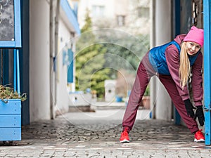 Sporty girl stretching outdoor on city street.