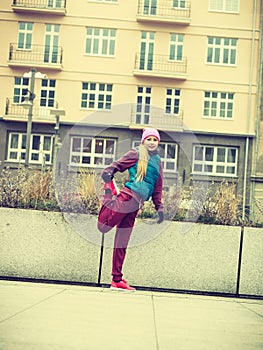 Sporty girl stretching outdoor on city street.