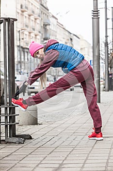 Sporty girl stretching outdoor on city street.