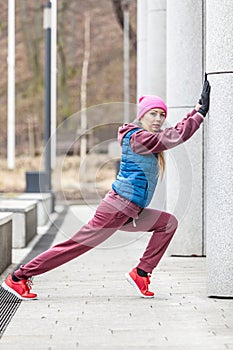 Sporty girl stretching outdoor on city street.