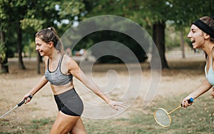 Sporty girls caused a commotion while playing badminton in the park. They are laughing and running around the court.