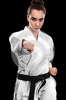 Sporty karate and taekwondo woman in white kimono with black belt on dark background. Sport concept with copy space.