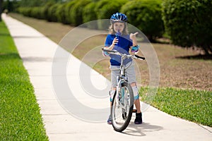 Sporty kid riding bike on a park. Child in safety helmet riding bicycle. Kid learns to ride a bike. Kids on bicycle