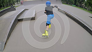 Sporty kids leisure boy rollerblades skating ramp