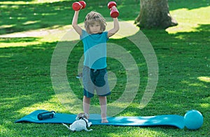 Sporty lifestyle concept. Sport yoga child with dumbbell. Boy exercising in park.