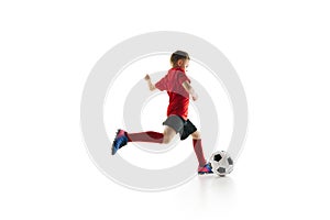 Sporty little boy, kicks ball to make perfect pass in motion against white studio background. Small football player