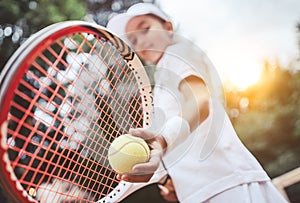 Sporty little girl preparing to serve tennis ball. Close up of beautiful yong girl holding tennis ball and racket. Child tennis